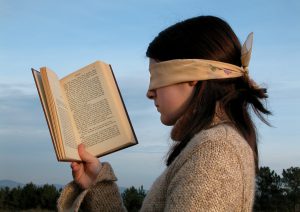 femme lisant un livre à voix haute les yeux bandés